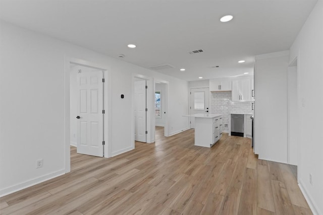 kitchen featuring tasteful backsplash, a center island, dishwasher, light countertops, and light wood-style flooring