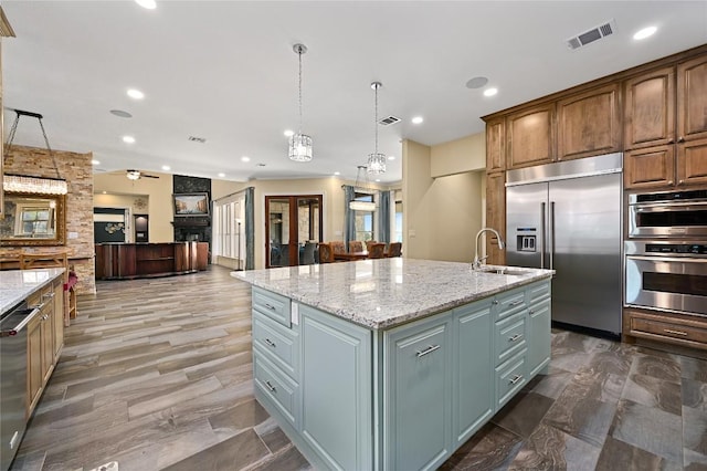 2624 University Club Dr, Austin, TX 78732 - kitchen with visible vents, a center island with sink, appliances with stainless steel finishes, hanging light fixtures, and a sink