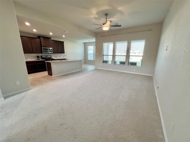 4413 Shady Hill Ln, Pflugerville, TX 78660 - kitchen featuring stainless steel microwave, baseboards, a ceiling fan, open floor plan, and a sink