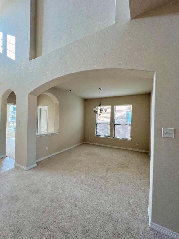 4413 Shady Hill Ln, Pflugerville, TX 78660 - spare room with a chandelier, light colored carpet, arched walkways, and baseboards
