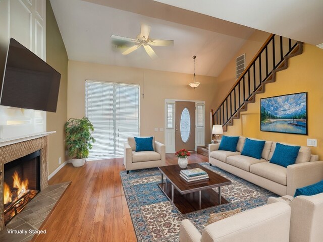16501 Spotted Eagle Dr, Leander, TX 78641 - living area with a ceiling fan, a tiled fireplace, light wood-style floors, lofted ceiling, and stairway