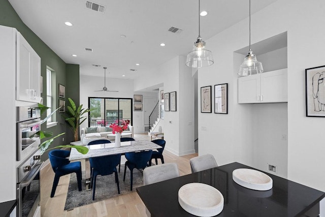 dining area featuring light wood-style floors, stairs, and visible vents