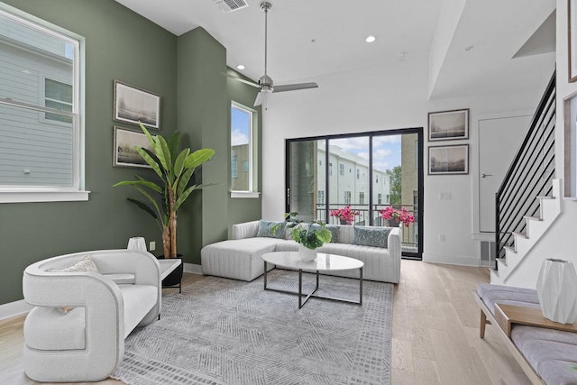 living area with stairway, baseboards, light wood-style flooring, and visible vents