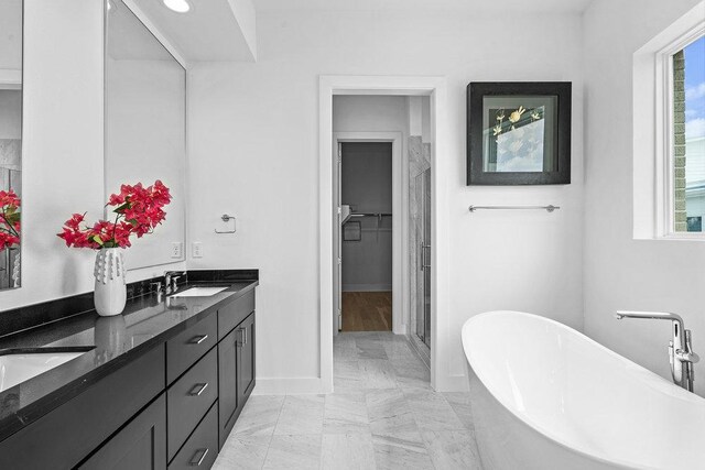 full bath with double vanity, a shower stall, a sink, baseboards, and a soaking tub