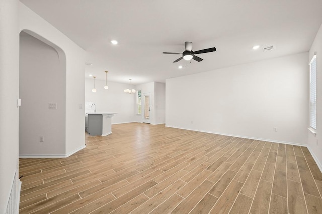 12106 Cantabria Rd, Austin, TX 78748 - unfurnished living room featuring a ceiling fan, light wood-style flooring, recessed lighting, arched walkways, and plenty of natural light