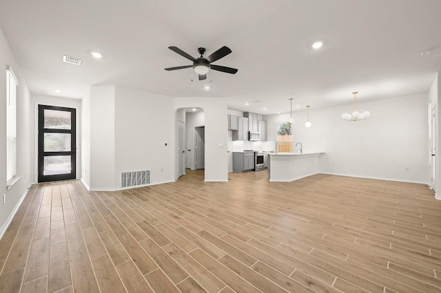 12106 Cantabria Rd, Austin, TX 78748 - unfurnished living room with ceiling fan, a chandelier, arched walkways, light wood finished floors, and recessed lighting