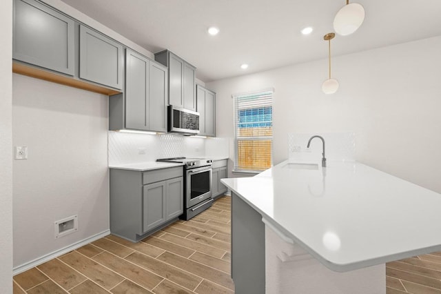 12106 Cantabria Rd, Austin, TX 78748 - kitchen featuring stainless steel appliances, a peninsula, gray cabinets, wood tiled floors, and light countertops