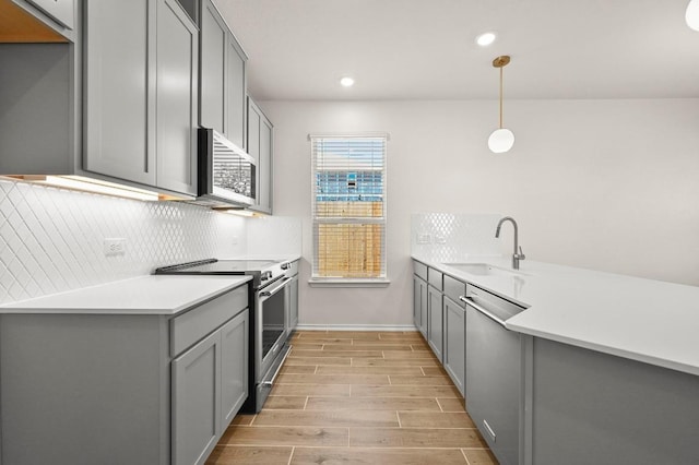 12106 Cantabria Rd, Austin, TX 78748 - kitchen featuring appliances with stainless steel finishes, gray cabinetry, decorative backsplash, wood finish floors, and light countertops