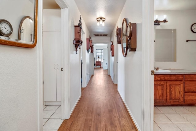 491 Herron Trl, Mcdade, TX 78650 - hallway featuring light wood-style floors, a sink, and baseboards