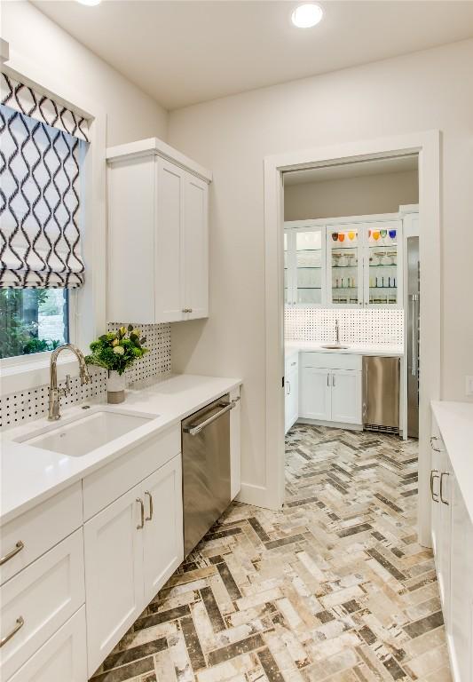 kitchen featuring a sink, white cabinets, light countertops, brick floor, and dishwasher