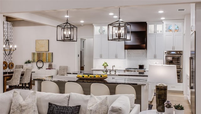 kitchen featuring visible vents, a chandelier, open floor plan, decorative backsplash, and light wood-style floors