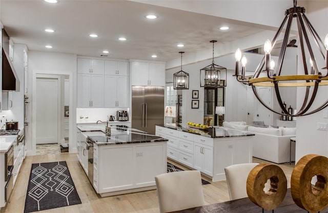 kitchen featuring a center island with sink, white cabinets, light wood-type flooring, and built in fridge