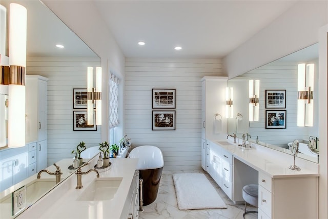 bathroom with recessed lighting, a freestanding bath, marble finish floor, and vanity
