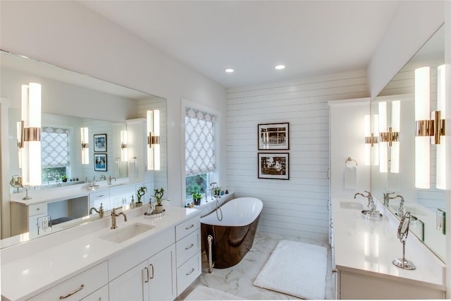 full bathroom with marble finish floor, two vanities, a sink, recessed lighting, and a freestanding bath