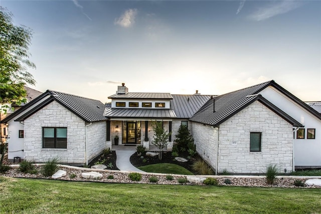view of front of property with stone siding, metal roof, a standing seam roof, and a front yard