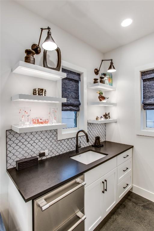 kitchen with dishwasher, dark countertops, and a sink