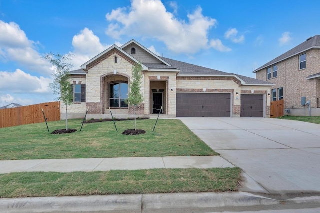 view of front facade featuring fence, an attached garage, stone siding, a front yard, and driveway