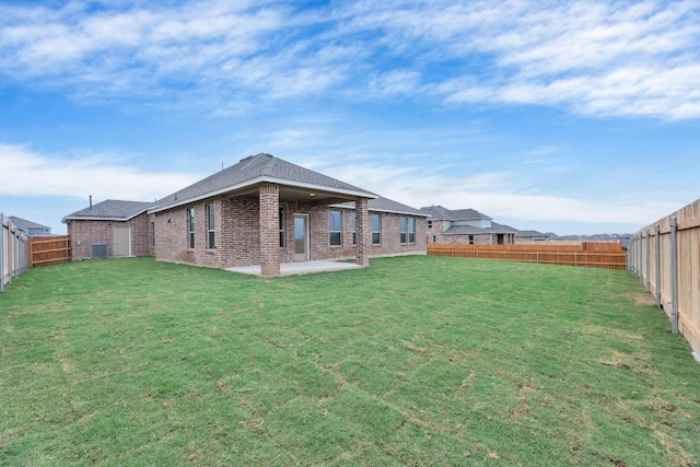 rear view of house featuring brick siding, a fenced backyard, a yard, and a patio