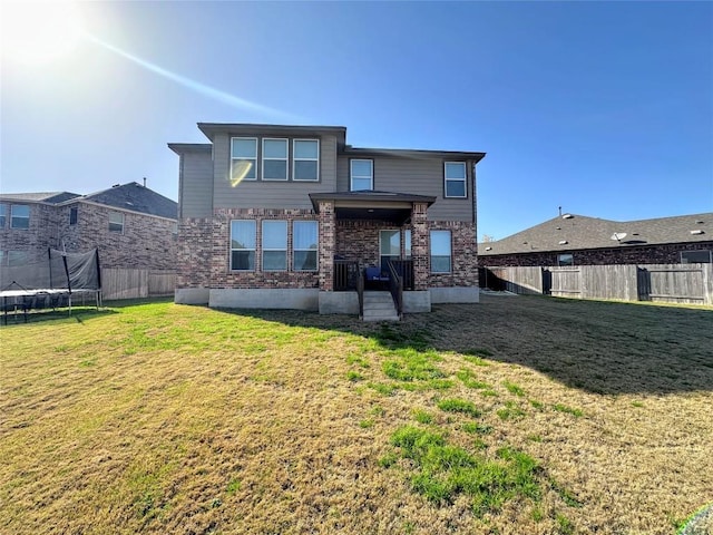 1208 Ravenside Cv, Leander, TX 78641 - back of house with a trampoline, a fenced backyard, and brick siding