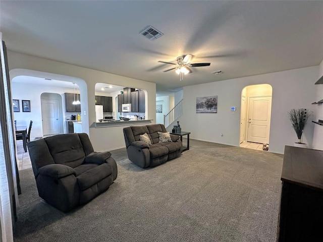 1208 Ravenside Cv, Leander, TX 78641 - carpeted living room with arched walkways, a ceiling fan, and stairway