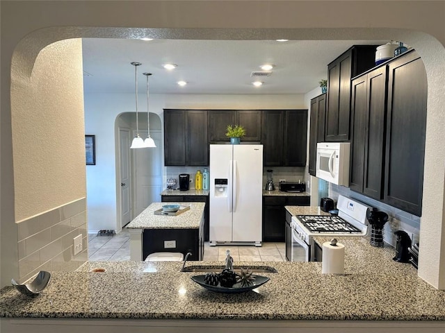1208 Ravenside Cv, Leander, TX 78641 - kitchen featuring white appliances, arched walkways, light stone countertops, and a peninsula