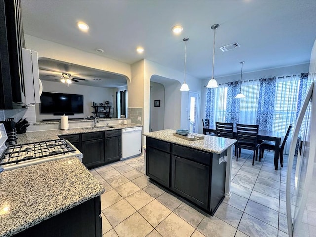 1208 Ravenside Cv, Leander, TX 78641 - kitchen with dishwasher, a ceiling fan, dark cabinetry, arched walkways, and light stone countertops