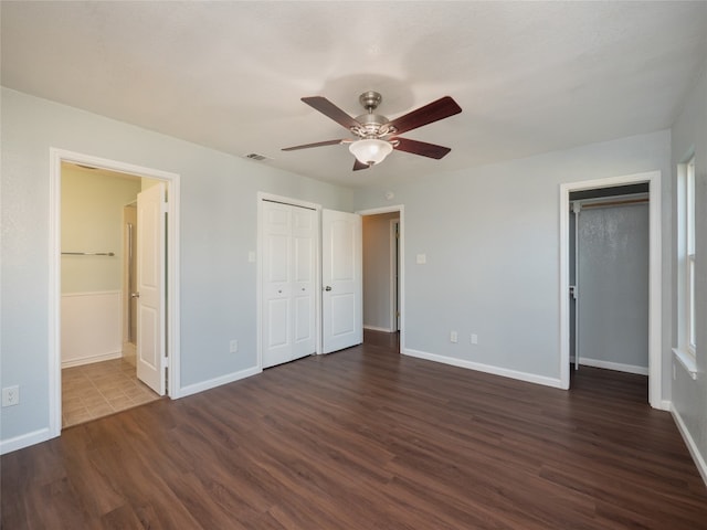 unfurnished bedroom featuring visible vents, baseboards, ceiling fan, dark wood finished floors, and ensuite bath