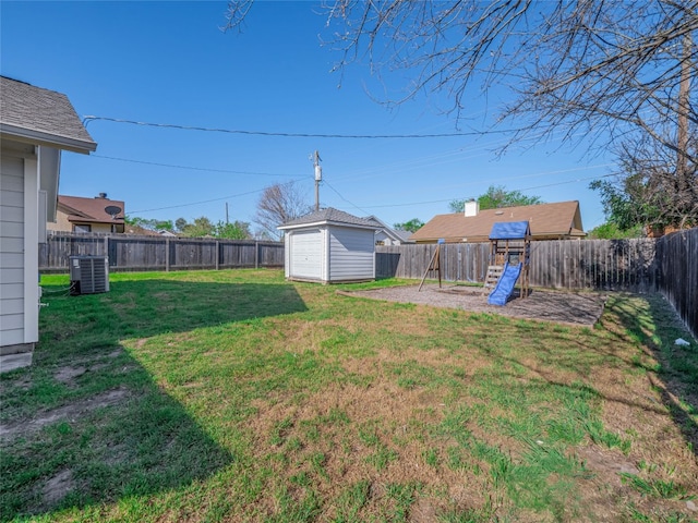 view of yard with an outbuilding, a storage unit, a fenced backyard, central AC unit, and a playground