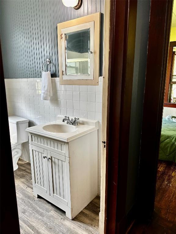 1106 Lexington St, Taylor, TX 76574 - bathroom featuring tile walls, toilet, wood finished floors, and vanity