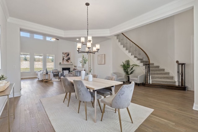 4709 Napoli Shore Dr, Leander, TX 78641 - dining space featuring stairs, ornamental molding, a fireplace, wood finished floors, and a chandelier