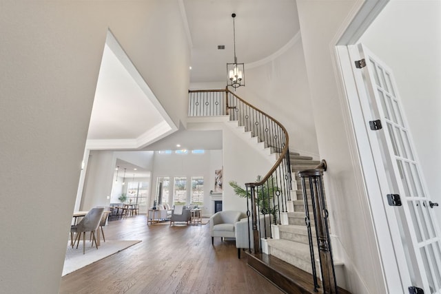 4709 Napoli Shore Dr, Leander, TX 78641 - entrance foyer with a chandelier, a high ceiling, stairs, wood finished floors, and a glass covered fireplace