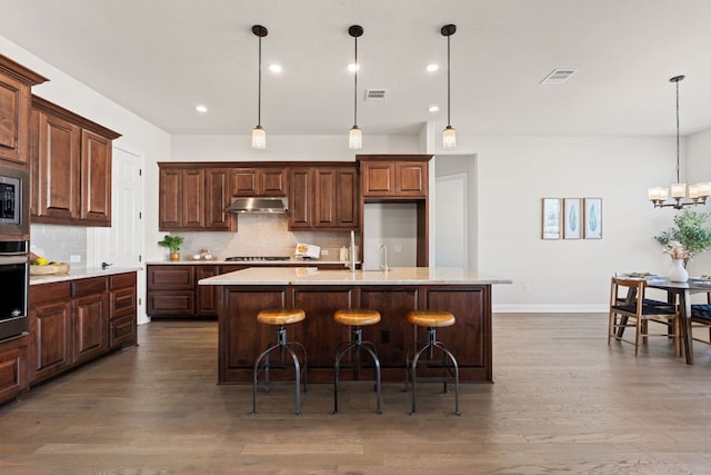 4709 Napoli Shore Dr, Leander, TX 78641 - kitchen with under cabinet range hood, backsplash, light countertops, and recessed lighting