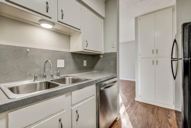 2712 Windswept Cv, Austin, TX 78745 - kitchen with freestanding refrigerator, dishwasher, light wood-type flooring, tasteful backsplash, and white cabinetry