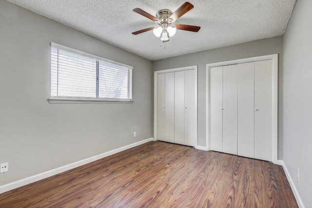2712 Windswept Cv, Austin, TX 78745 - unfurnished bedroom featuring two closets, wood finished floors, a textured ceiling, and ceiling fan
