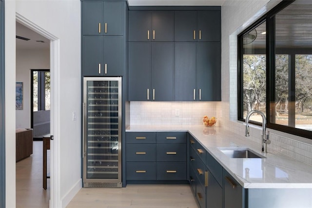 bar featuring bar area, a sink, tasteful backsplash, light wood-type flooring, and beverage cooler