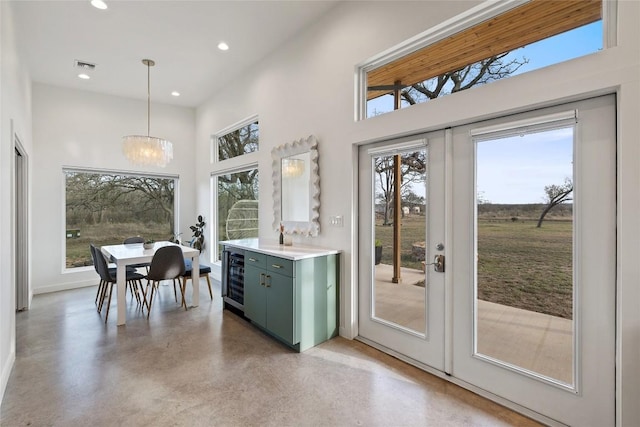 entryway featuring wine cooler, a towering ceiling, visible vents, finished concrete floors, and recessed lighting