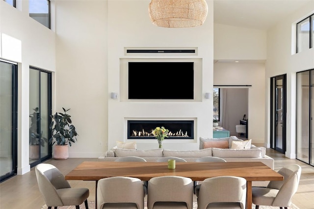 interior space with baseboards, light wood-style flooring, a towering ceiling, and a fireplace