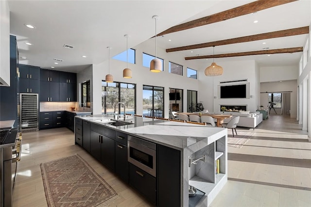 kitchen featuring a large island, dark cabinets, visible vents, a sink, and stainless steel microwave