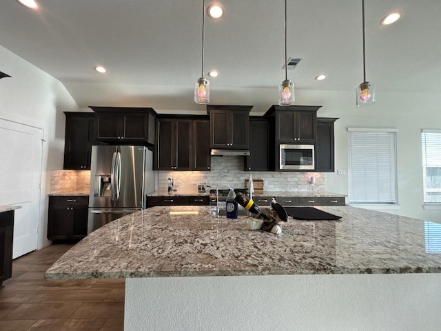 2905 Lago Costa Dr, La Marque, TX 77568 - kitchen with visible vents, under cabinet range hood, appliances with stainless steel finishes, decorative backsplash, and light stone countertops