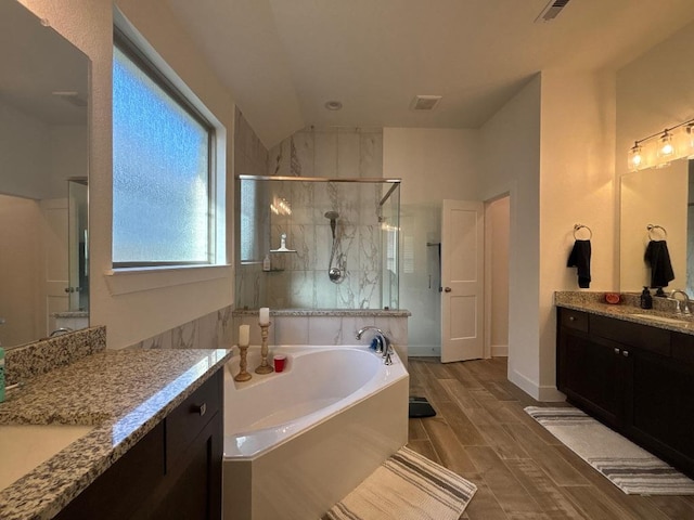 2905 Lago Costa Dr, La Marque, TX 77568 - full bath with a stall shower, a bath, two vanities, wood finished floors, and vaulted ceiling
