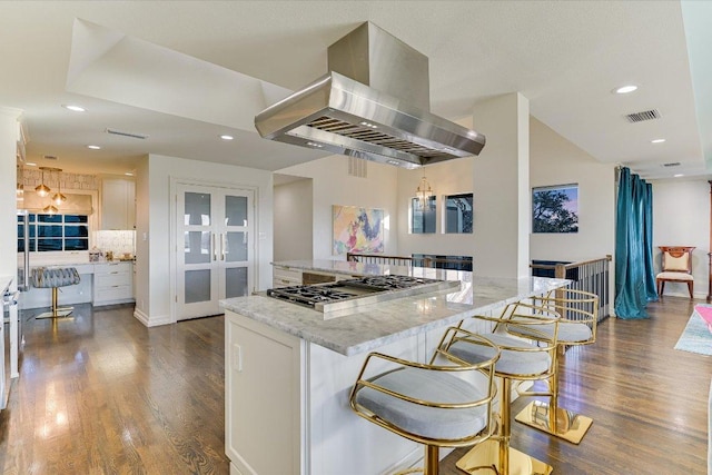 4732 Twin Valley Dr, Austin, TX 78731 - kitchen with stainless steel gas stovetop, island range hood, tasteful backsplash, dark wood-type flooring, and light stone counters