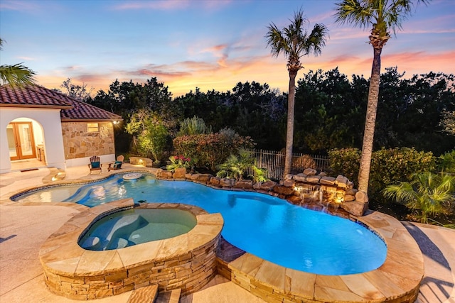 pool at dusk with fence, french doors, a fenced in pool, an in ground hot tub, and a patio area