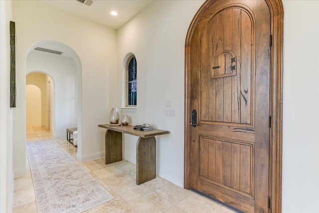 foyer entrance featuring visible vents, recessed lighting, baseboards, and arched walkways