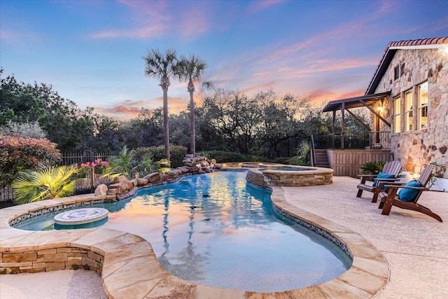 view of swimming pool featuring a pool with connected hot tub and fence