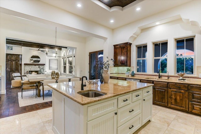 kitchen with tasteful backsplash, light stone countertops, a center island with sink, recessed lighting, and a sink