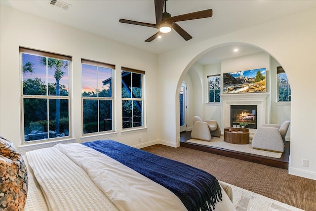 bedroom featuring visible vents, baseboards, carpet floors, and a glass covered fireplace
