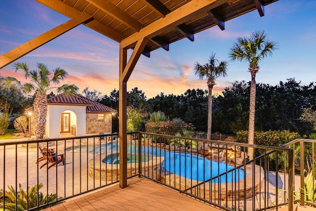 balcony at dusk with a patio area and a pool with connected hot tub