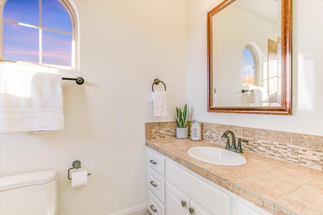 bathroom with backsplash, toilet, and vanity