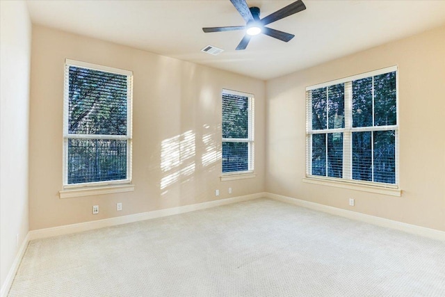 unfurnished room with carpet, a ceiling fan, visible vents, baseboards, and plenty of natural light