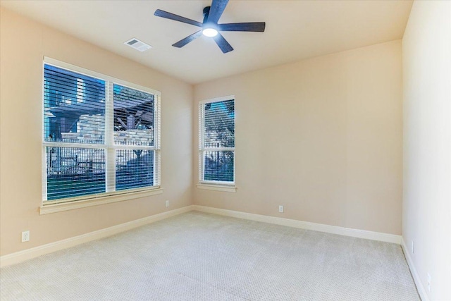 carpeted empty room with visible vents, baseboards, and a ceiling fan